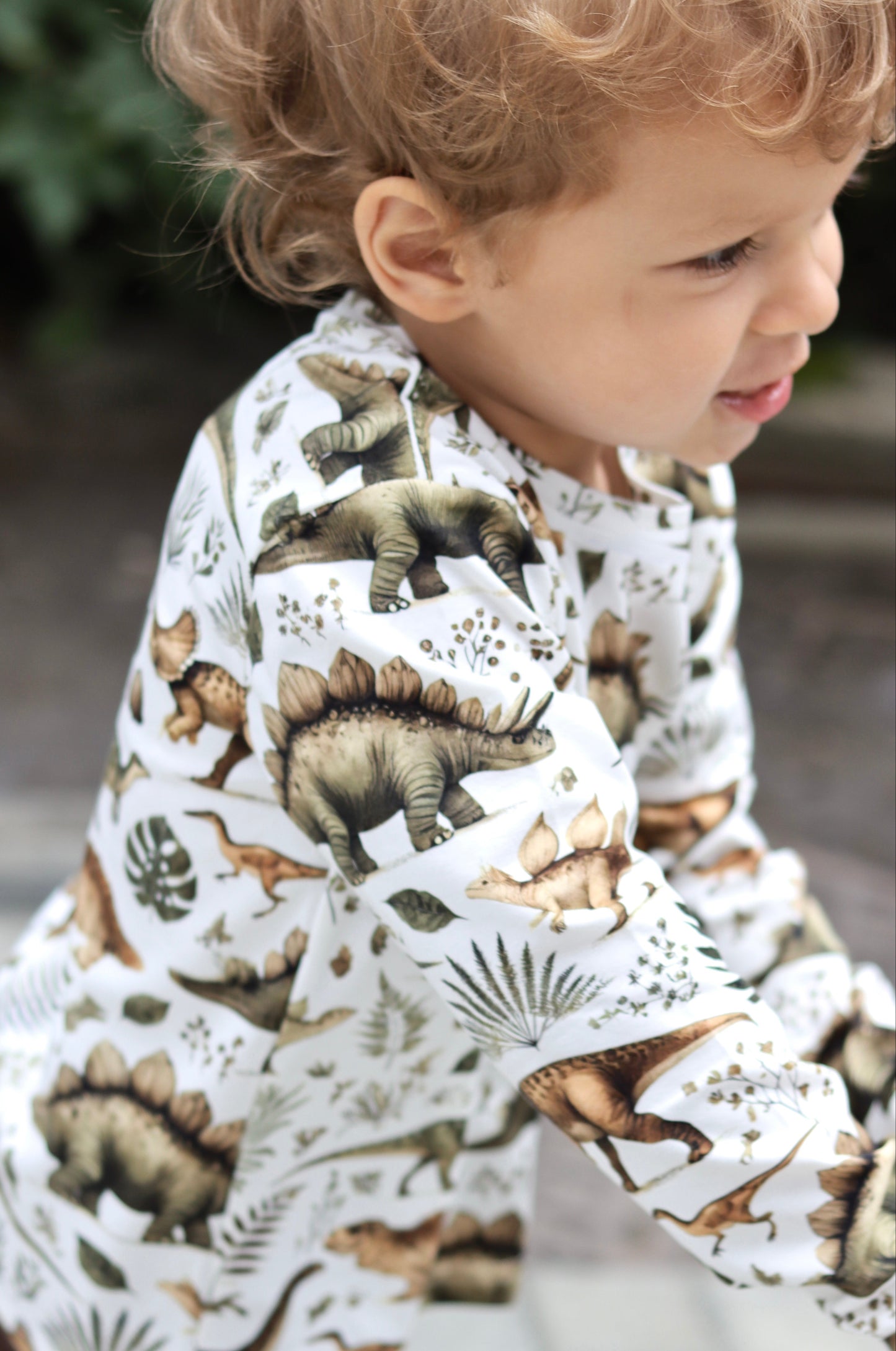 Child wearing a dinosaur-patterned shirt outdoors