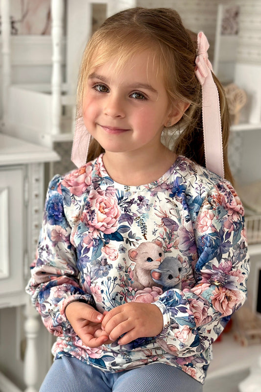 Young girl wearing a floral sweater with teddy bears in a home setting