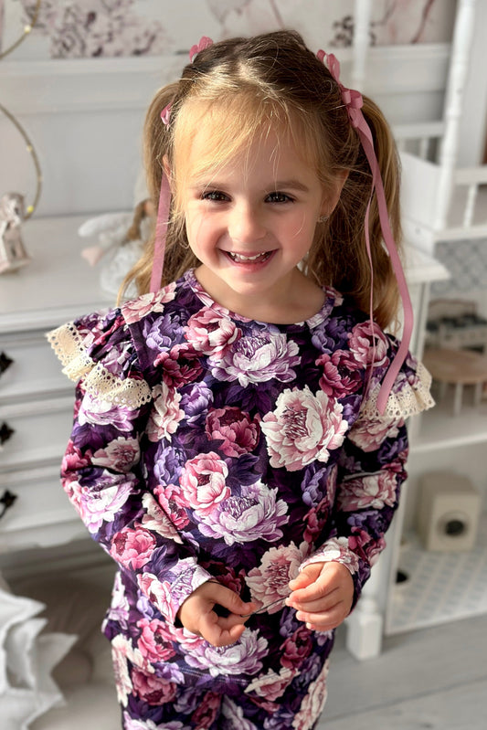 Young girl in a floral dress standing in a decorated room.