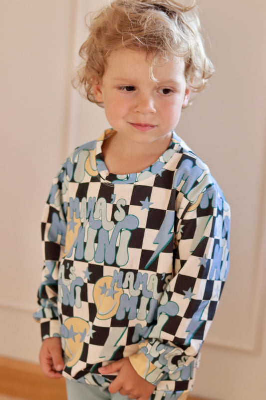 Child wearing a checkered shirt with abstract patterns in a room.