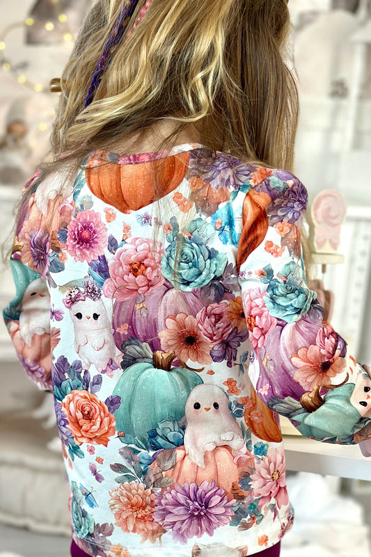 Person wearing a colorful shirt with floral and animal designs in a home setting.